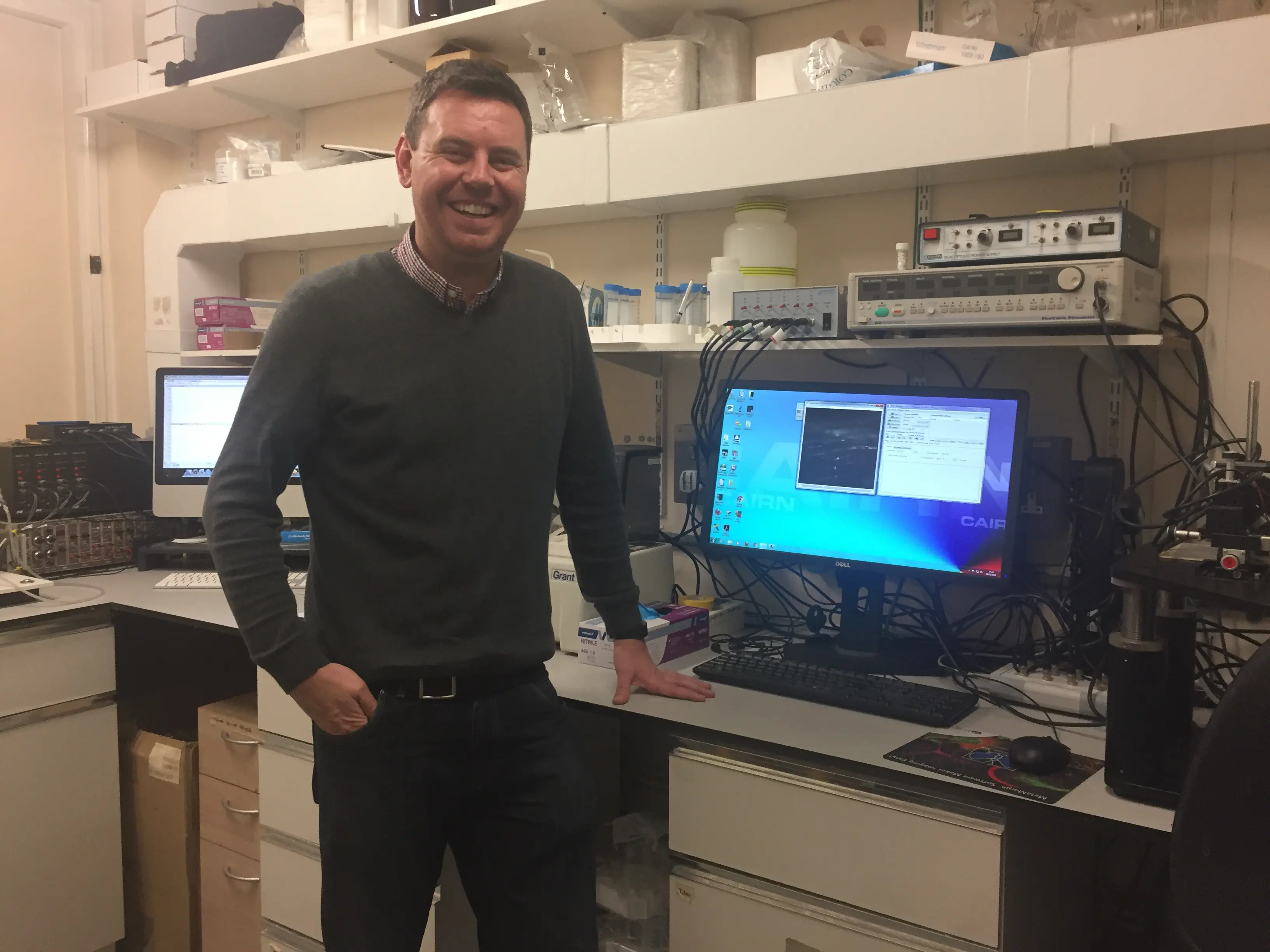 Dr Conor McCann standing by his computer in his laboratory