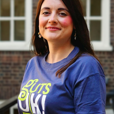 Amy is smiling at the camera and wearing a navy blue Guts UK t-shirt.