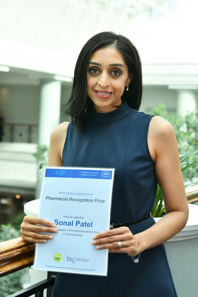 Sonal is holding her awards certificate and smiles at the camera