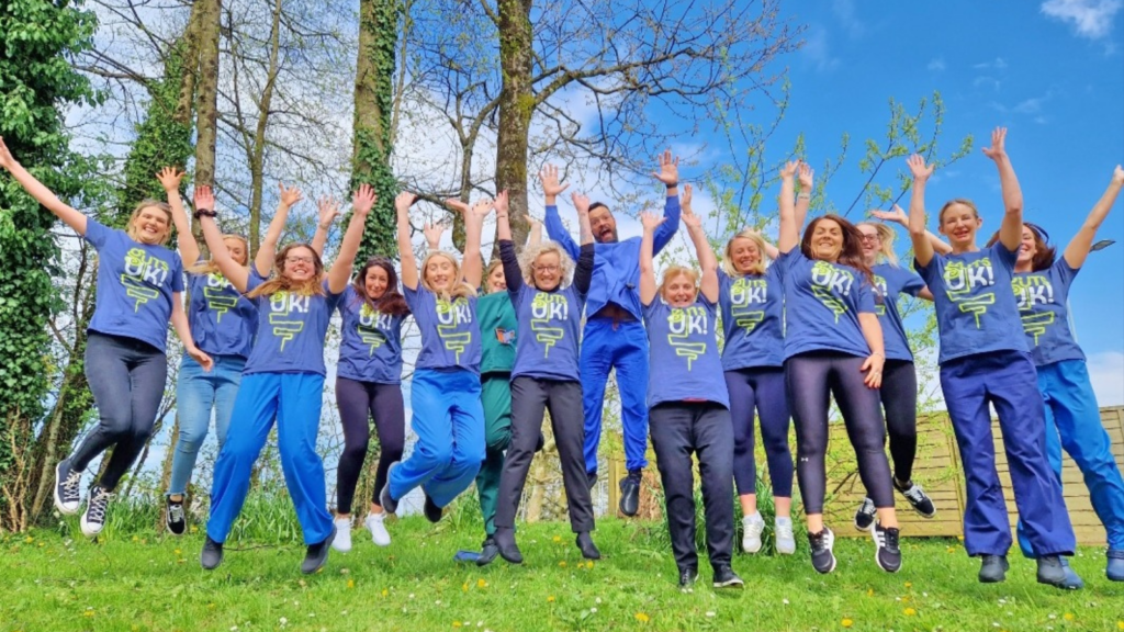 A group of people waring Guts UK t-shirts jumping in the air in celebration.