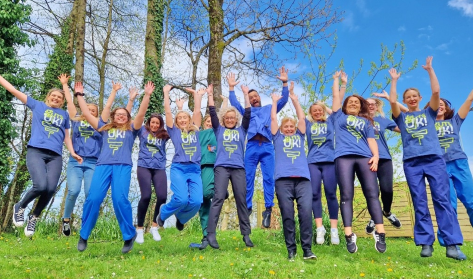 A group of people waring Guts UK t-shirts jumping in the air in celebration.