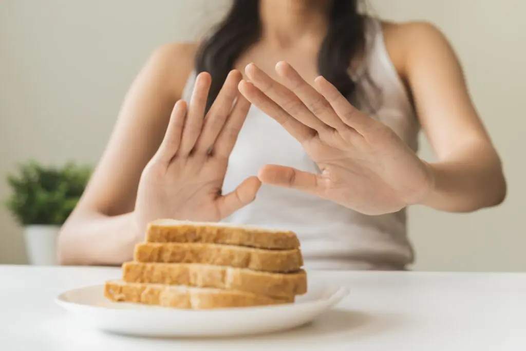 A woman's hands are raised in front of a plate of bread.
