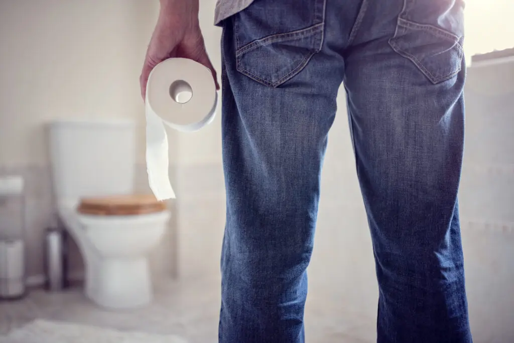 Man holding toilet tissue roll in bathroom 
