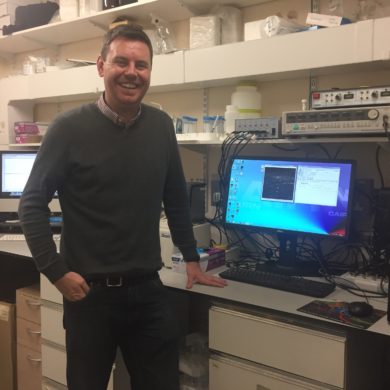 Dr Conor McCann standing by his computer in his laboratory