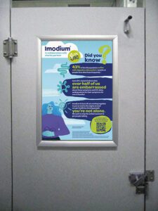 Imodium and Guts UK advert on the back of a public toilet door