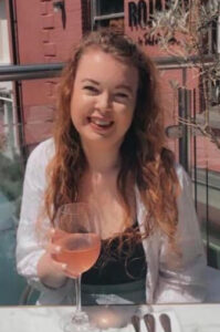Picture of Caroline smiling at the camera with a wine glass in her hand.