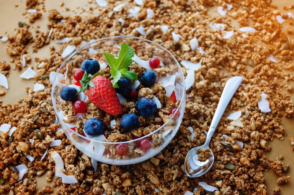 Strawberries, blueberries, oats and yoghurt in a clear glass bowl