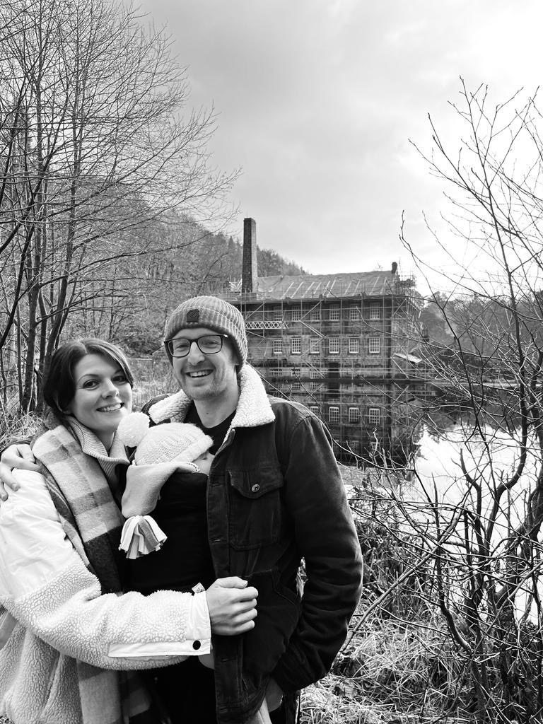 Lizzie, April and Ross smiling at the camera with an old building in the background across a lake.