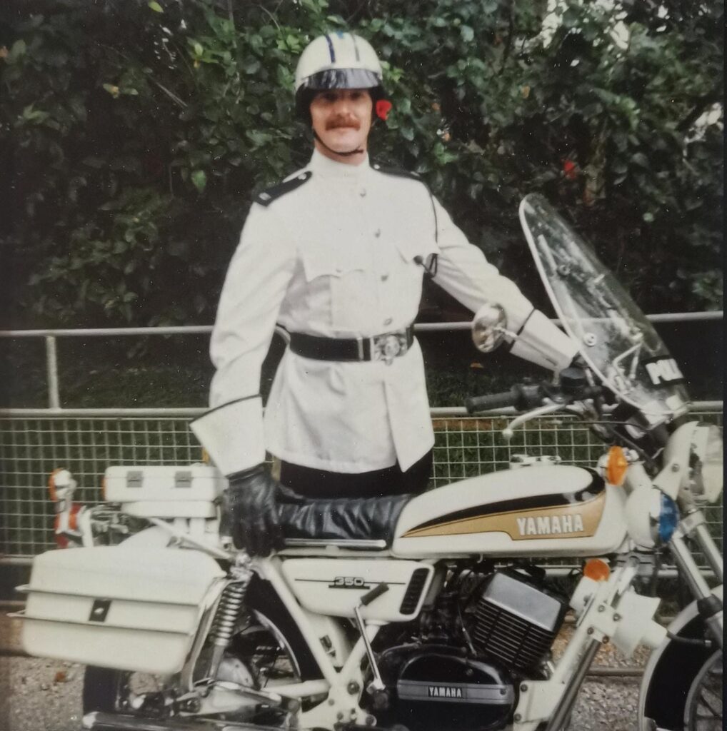 Tony is pictured wearing his police uniform, in Bermuda, with his police bike