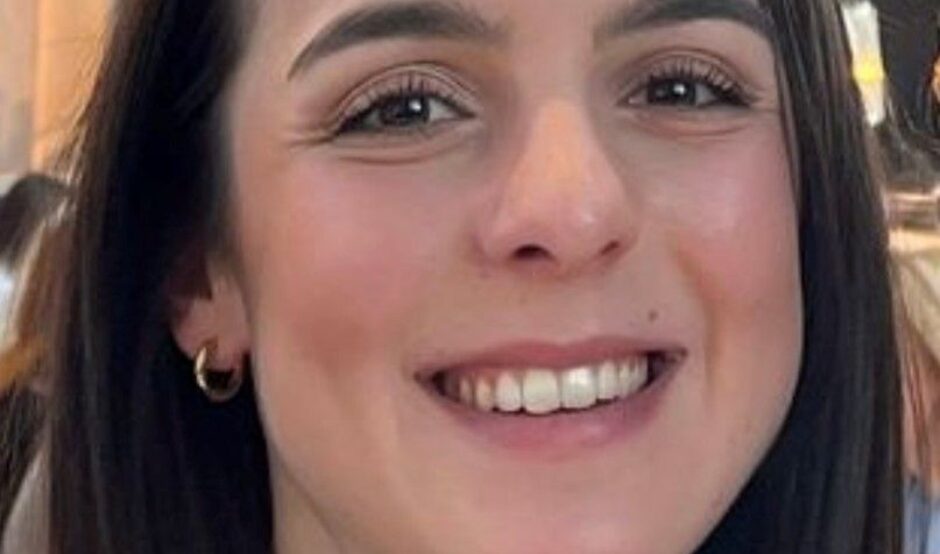 Katerina has long dark brown hair and is smiling at the camera in this headshot
