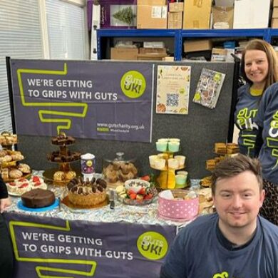 A group of colleagues from William's pumbing merchant stood next to a table full of baked goods, decorated with Guts UK branding.