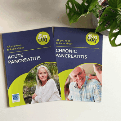 A birds eye view of Guts UK acute pancreatitis and chronic pancreatitis leaflets, on a white table, with a lush, green, cheese plants to the top right.