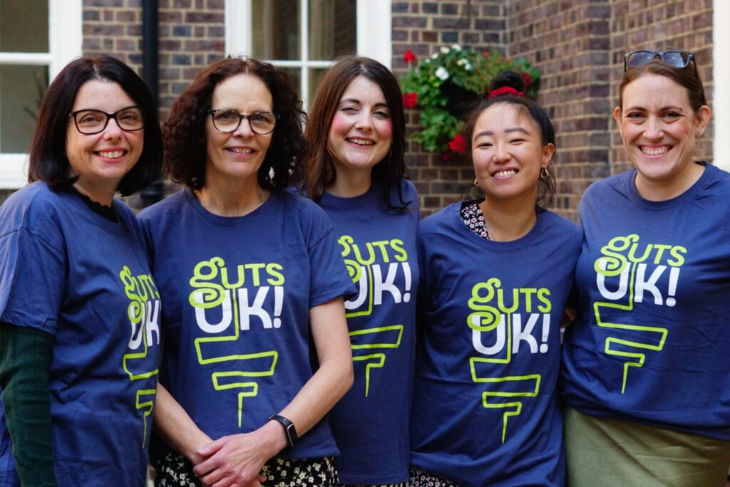 Cherylyn, Melanie, Amy, Leeona and Katie are stood smiling, wearing blue Guts UK t-shirts.