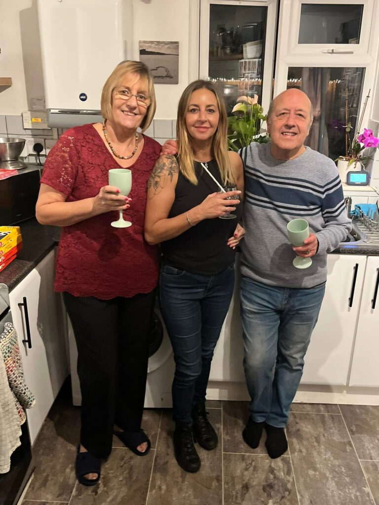 Charlie with his wife, and daughter, Sarah, stood in the kitchen smiling at the camera.