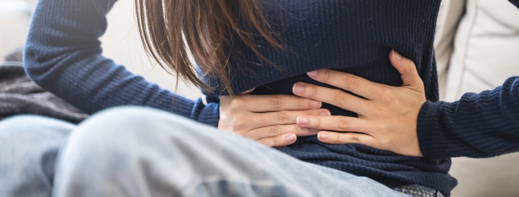 A woman gripping her stomach from abdominal pain