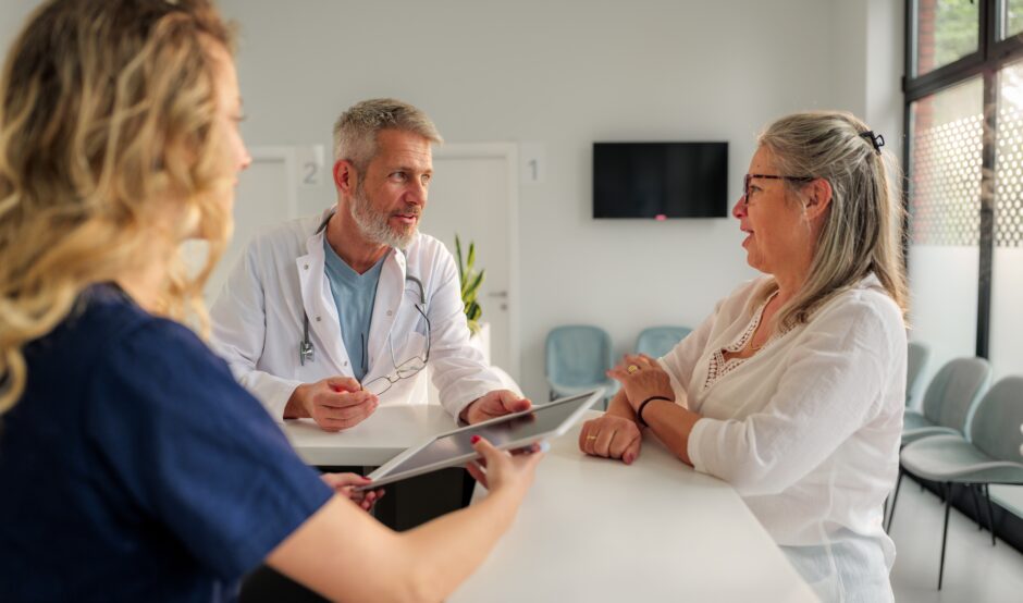 A patient talks to a doctor and a nurse in a hospital.