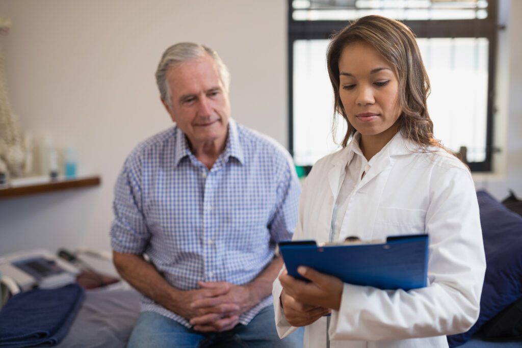 Close up of senior male patient and female healthcare professional looking at a file in hospital
